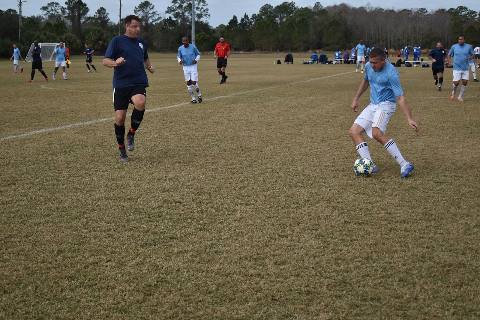 Soccer players in blue uniforms compete on a grassy field during a game.