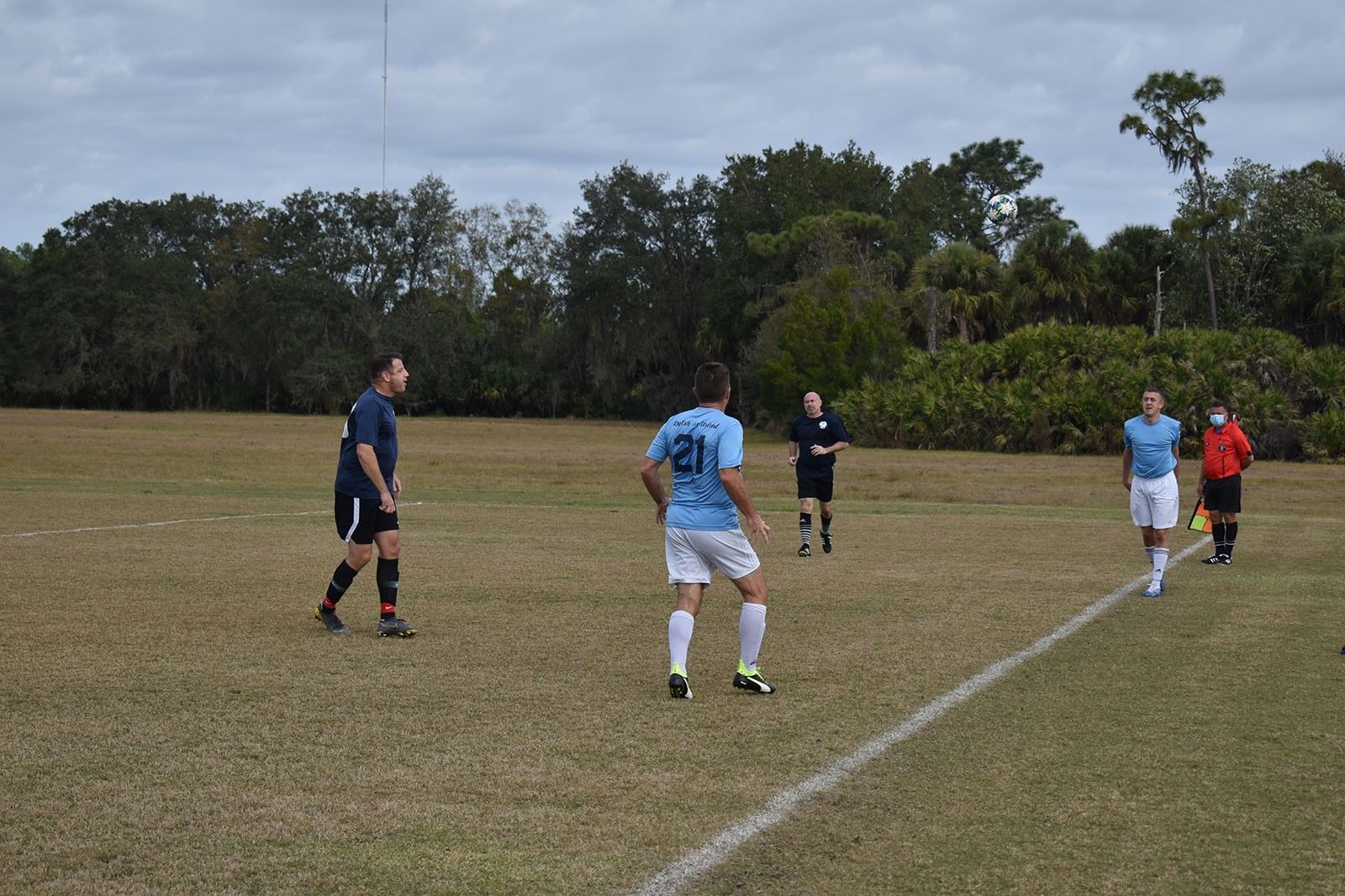 Soccer players on a grassy field during a match, with one player running toward the ball.