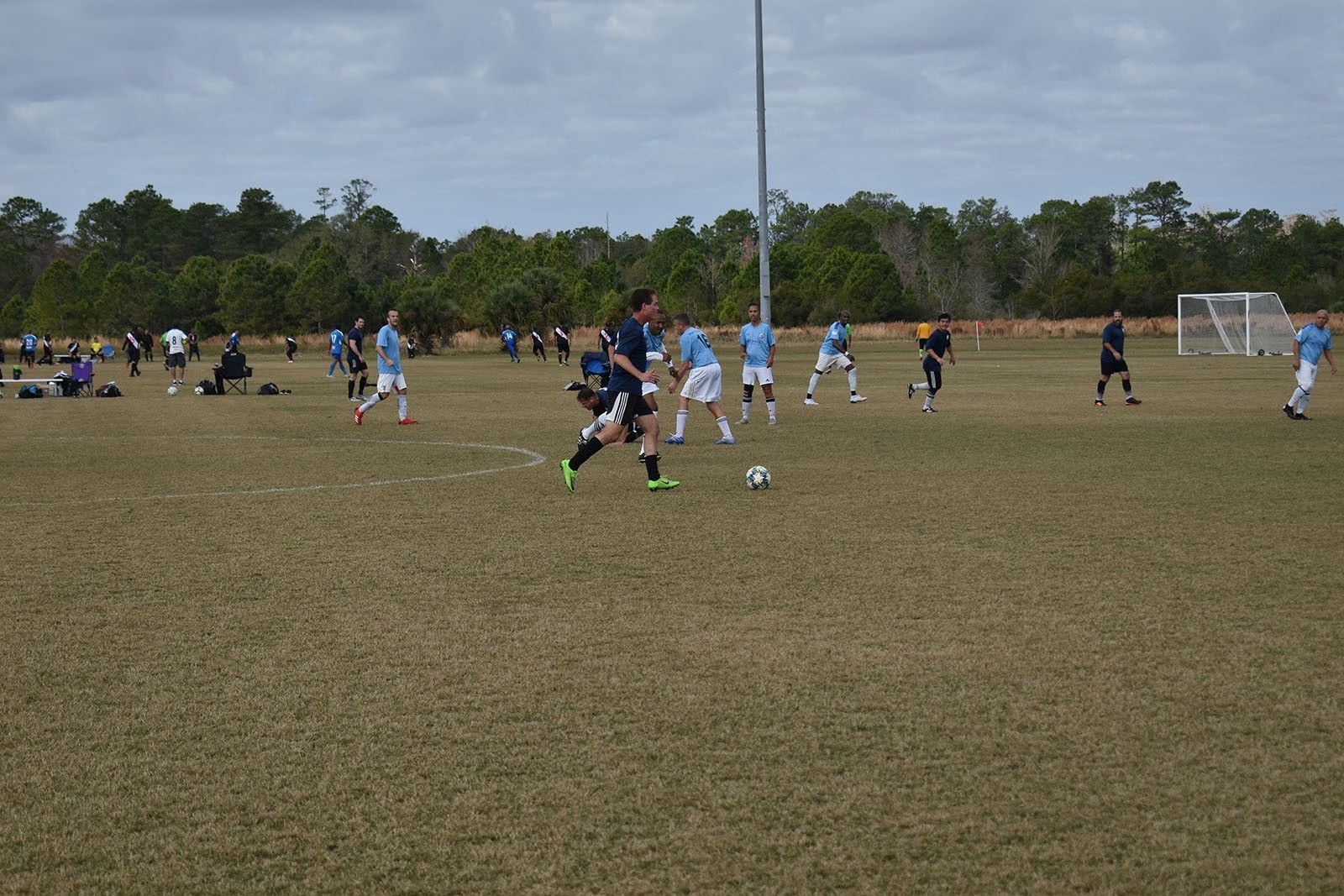 Youth soccer game on a grassy field with players in blue and black chasing the ball