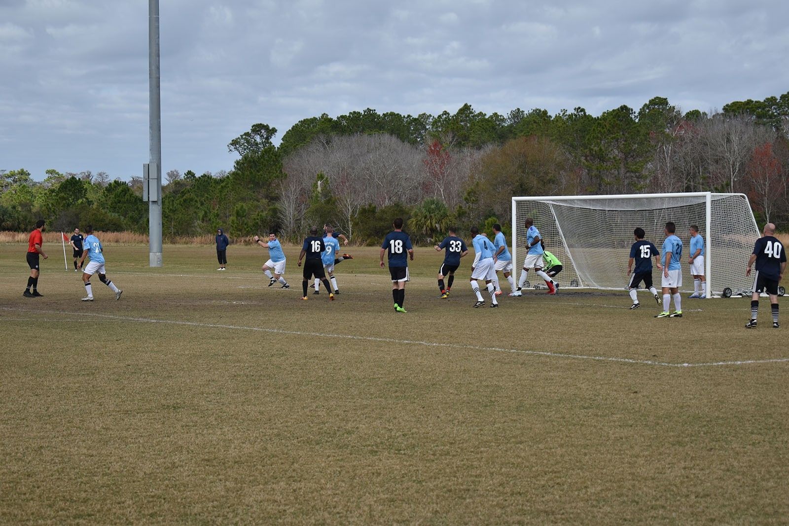 Soccer match near the goal, with players contesting the ball on a grassy field.