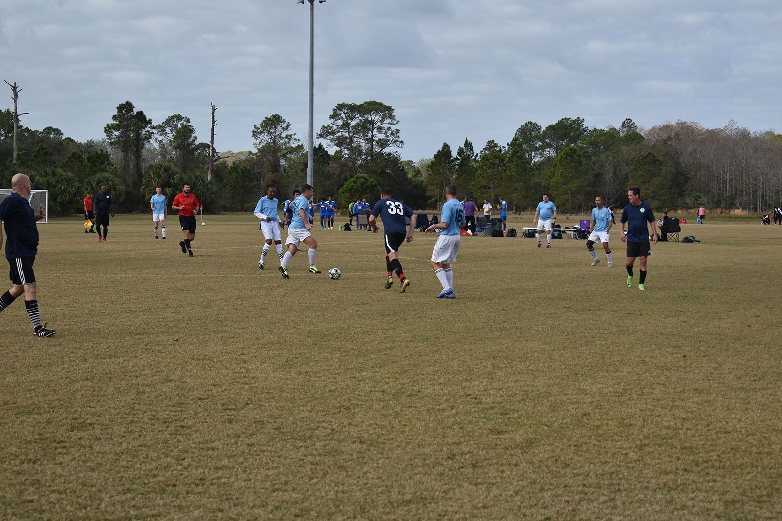 Youth soccer game on a grassy field, with players in blue and white uniforms running after the ball.