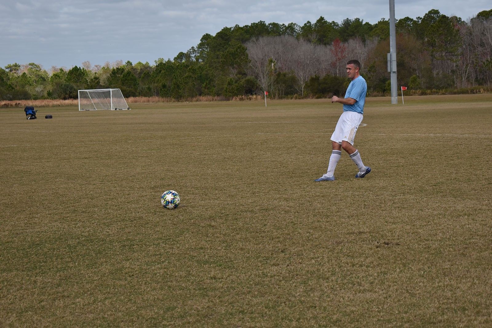 Soccer player in blue and white stands near a ball on an open field