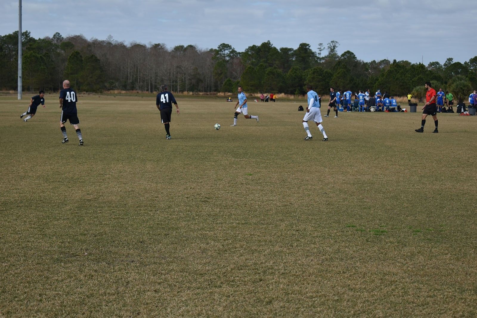 Soccer match on a grassy field with players in blue and black uniforms near the goal