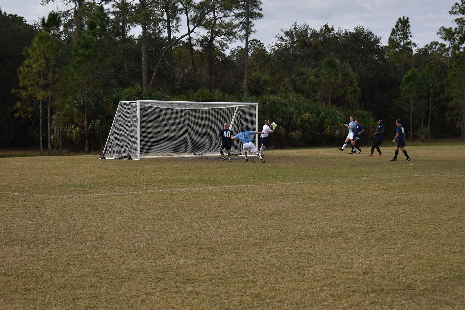 Soccer goal with players gathered near the net on a grassy field