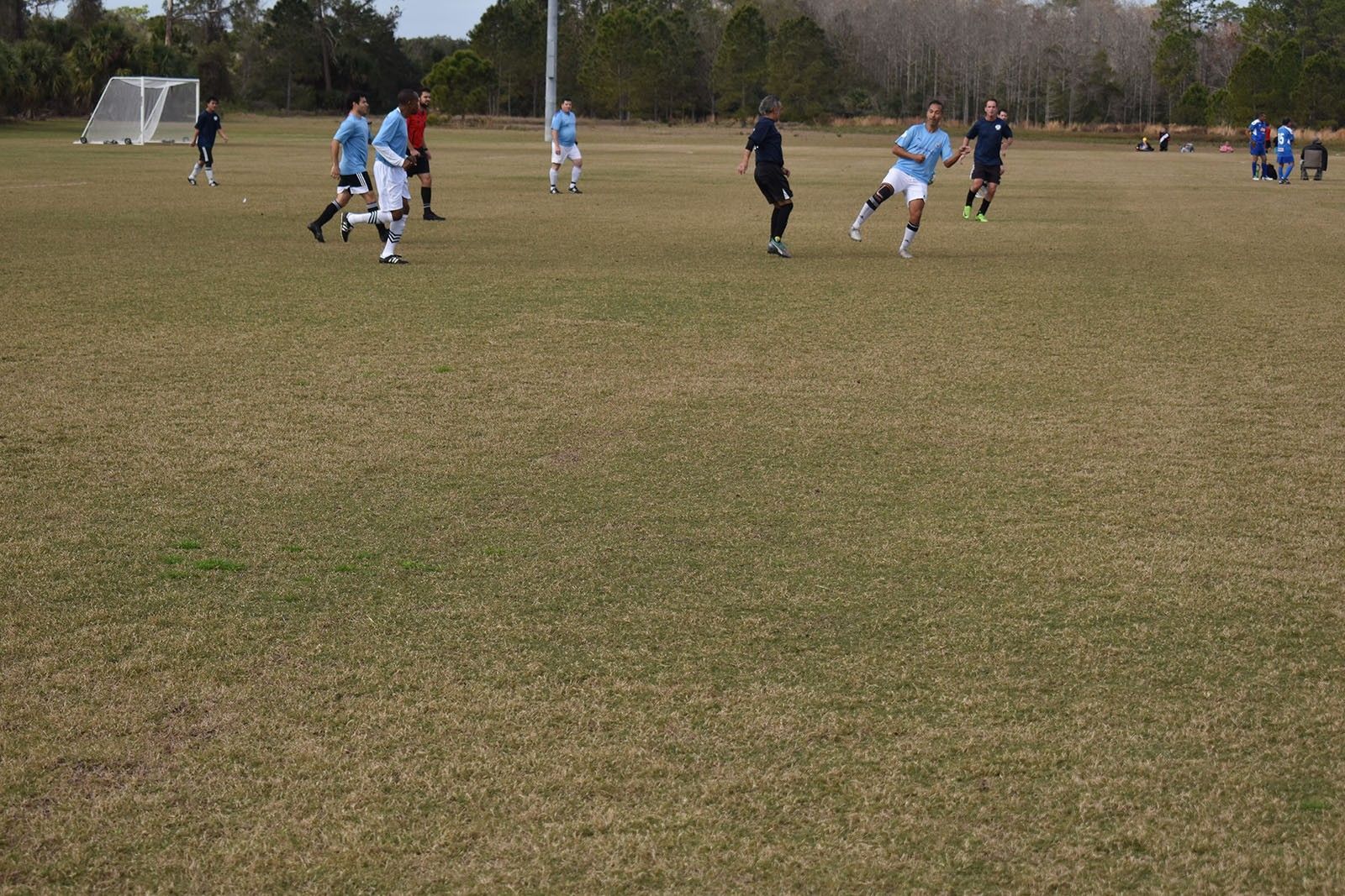 Soccer players in blue and black uniforms on a grassy field during a match.
