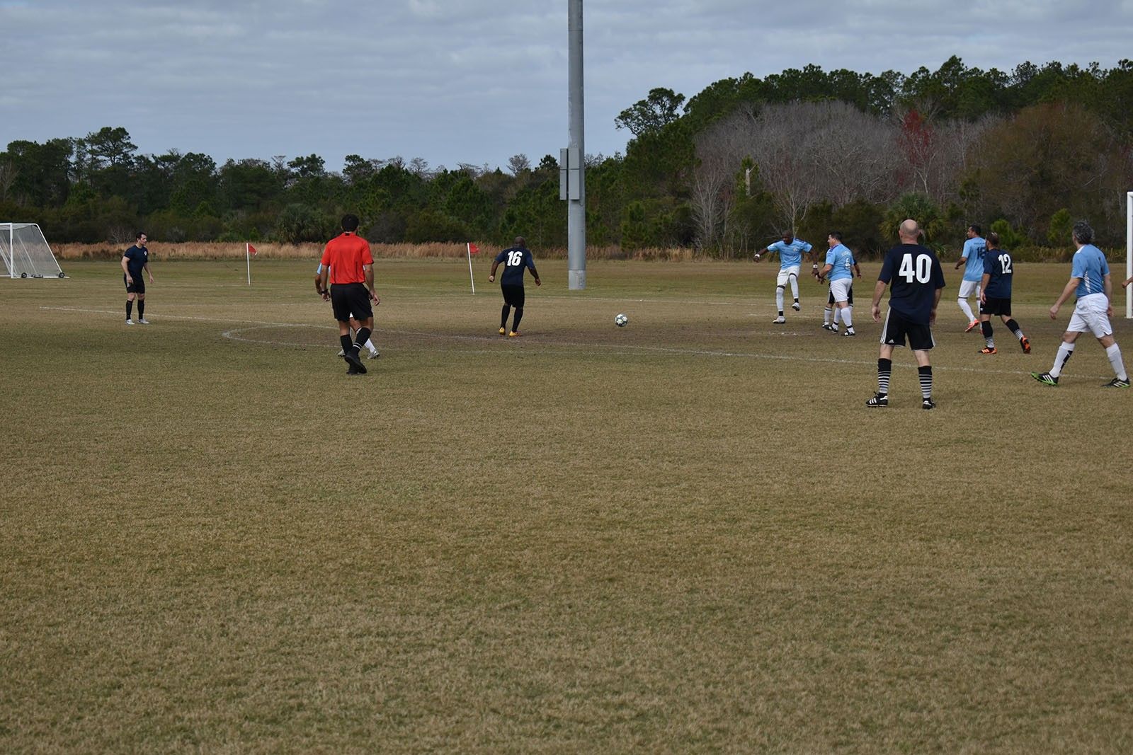 Soccer players in blue and black jerseys on a grassy field with a referee near midfield