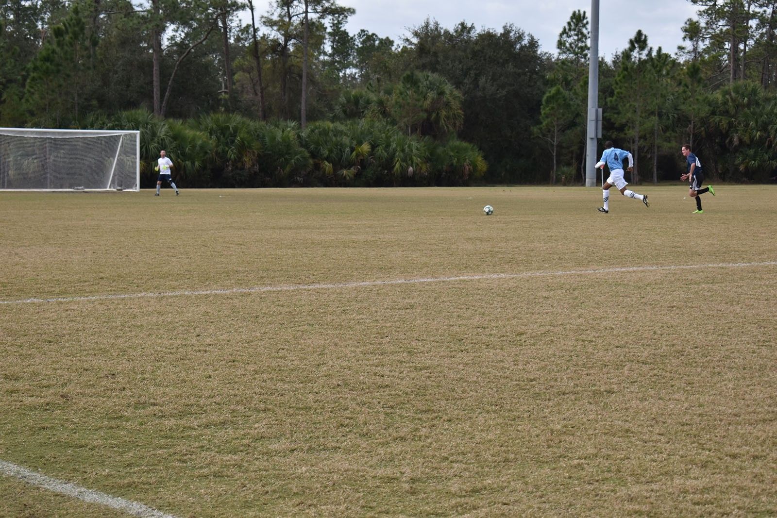 Soccer players on a field near the goal, with one player about to kick the ball.