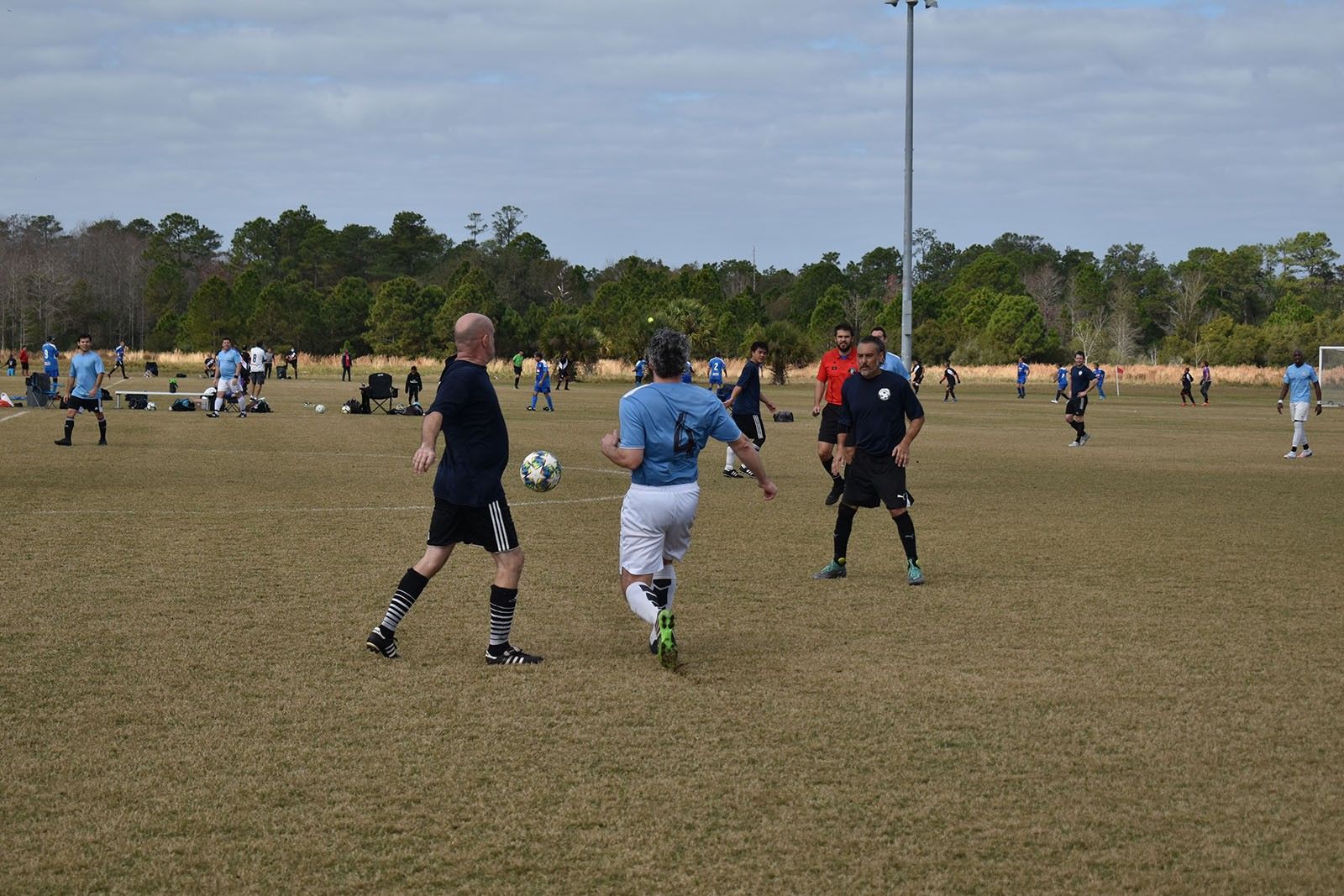 Soccer players in black, blue, and red uniforms on a grassy field during a match