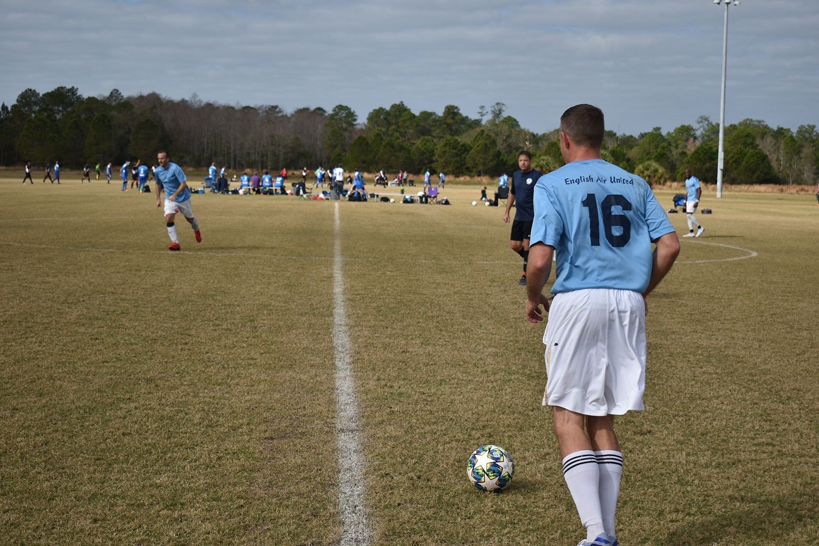 Soccer player in a blue jersey prepares to kick a ball on a grassy field during a match