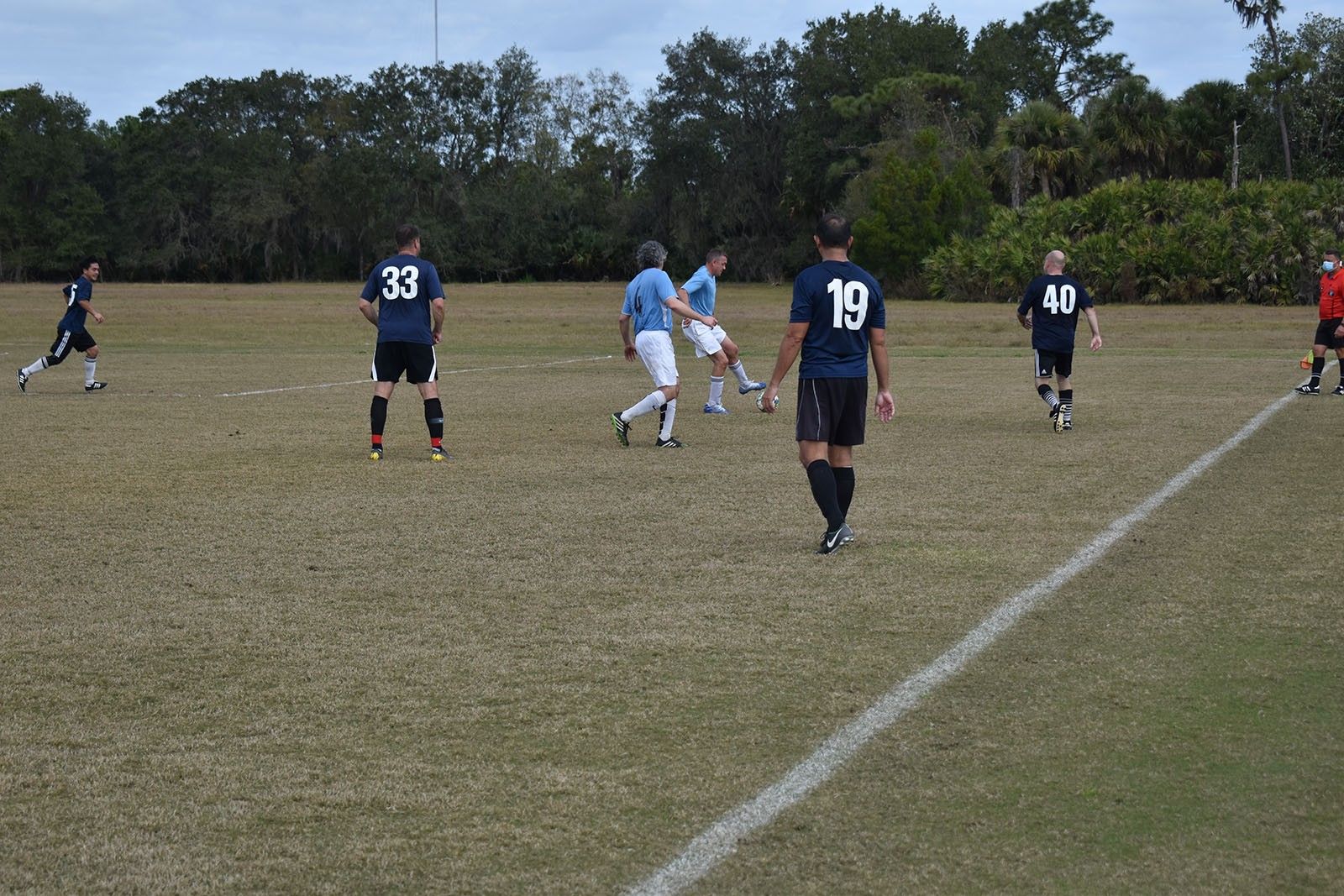 Soccer players in navy and white uniforms on a grassy field during a match