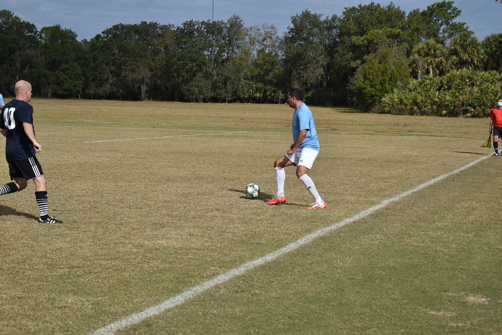 Soccer player in light blue dribbles the ball on a grassy field during a match.