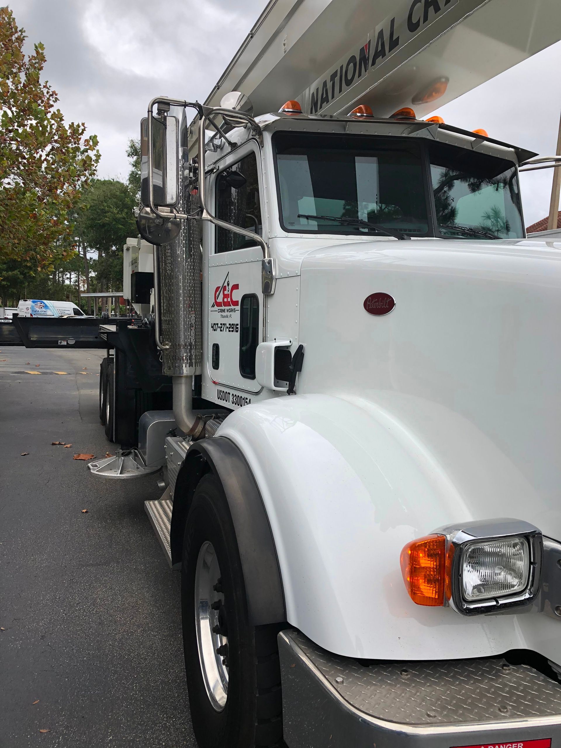 White utility bucket truck parked on a wet street, front view with extended boom arm.