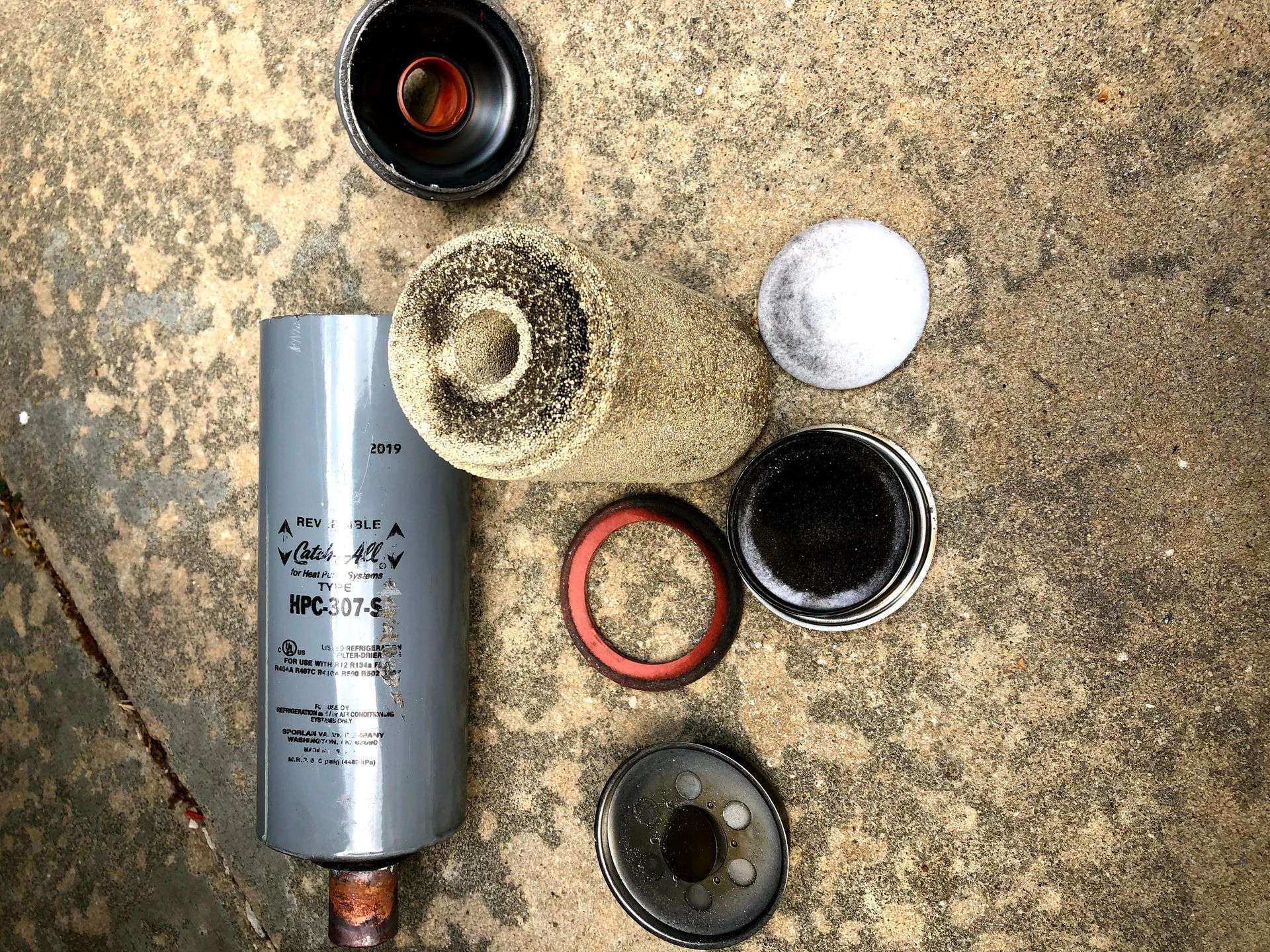 Hair product bottle and several open cosmetic jars arranged on a textured surface.