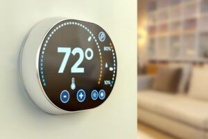 Digital thermostat displaying 72° on a wall, with a blurred living room in the background