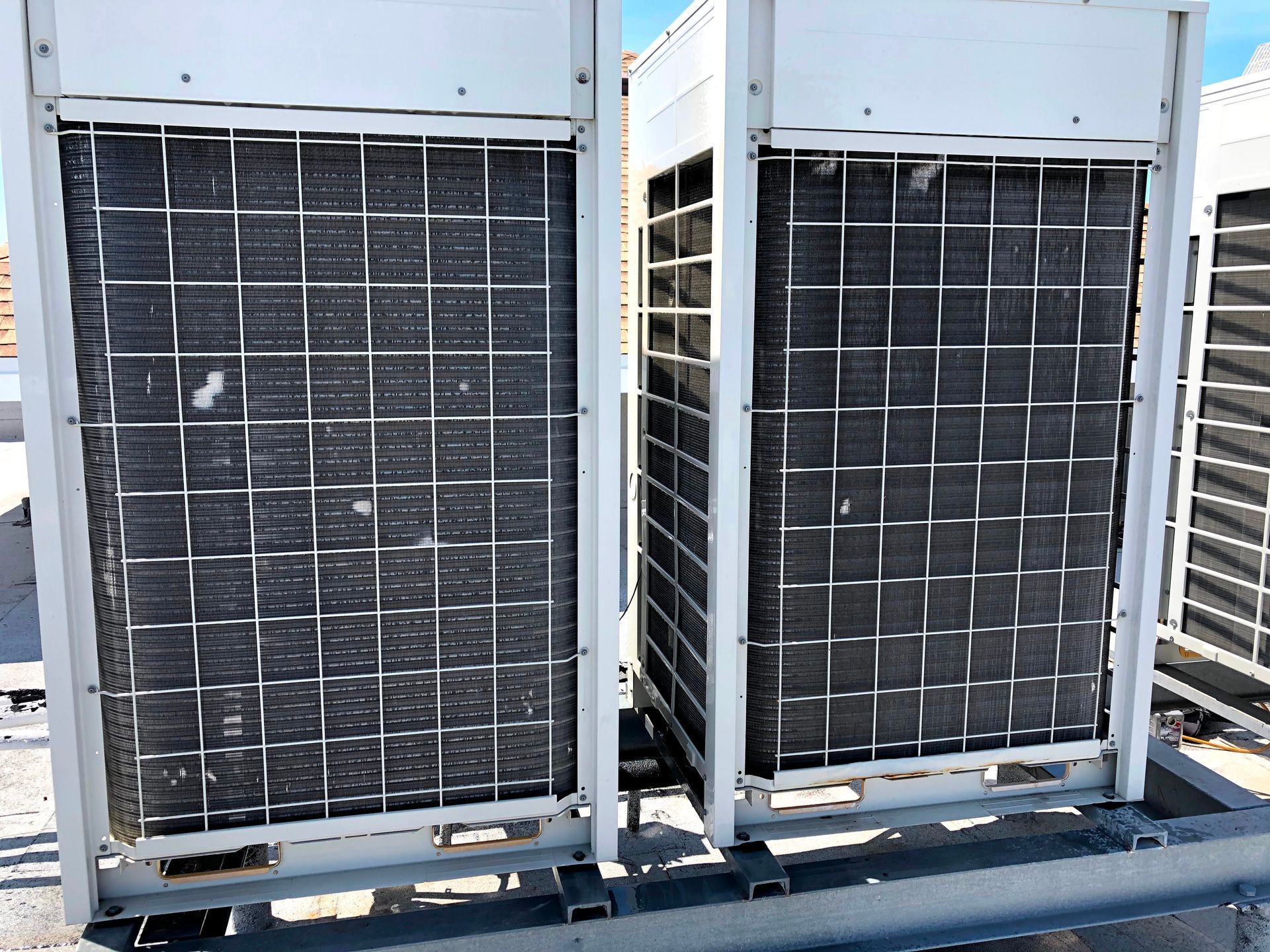 Two large rooftop HVAC condenser units with dark grilles on a metal platform outdoors