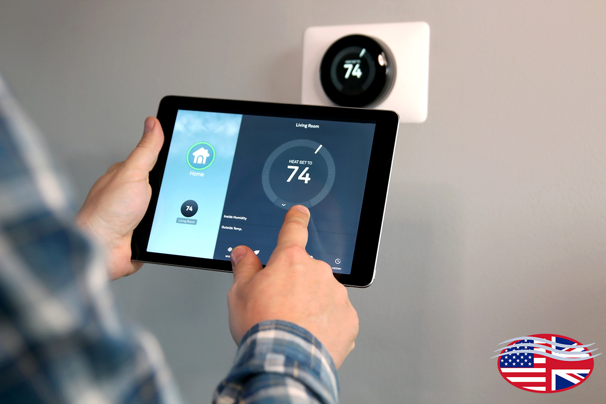 Person adjusting a wall-mounted smart thermostat using a tablet in a home setting