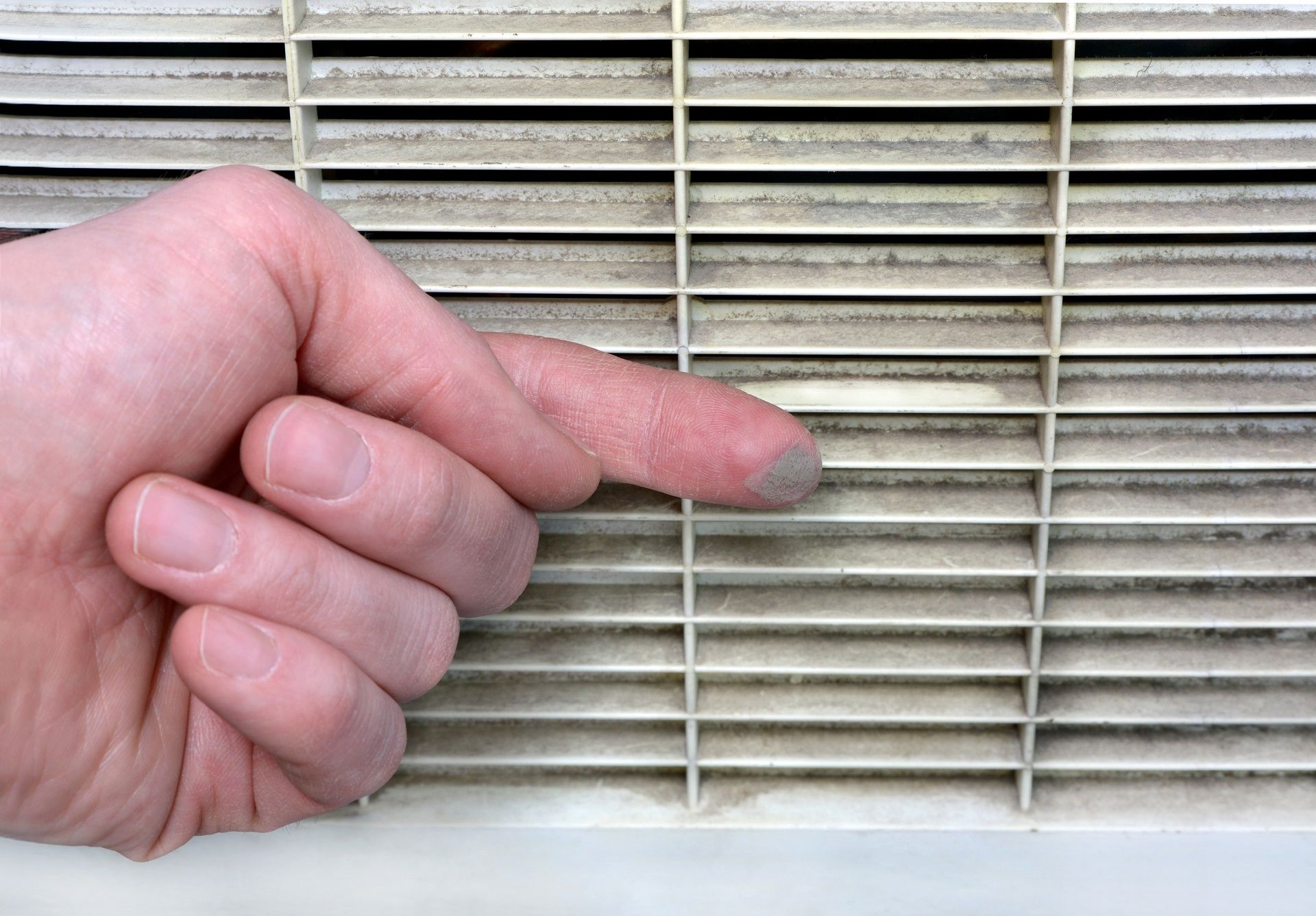 Hand pointing at a beige window blind or vent slats