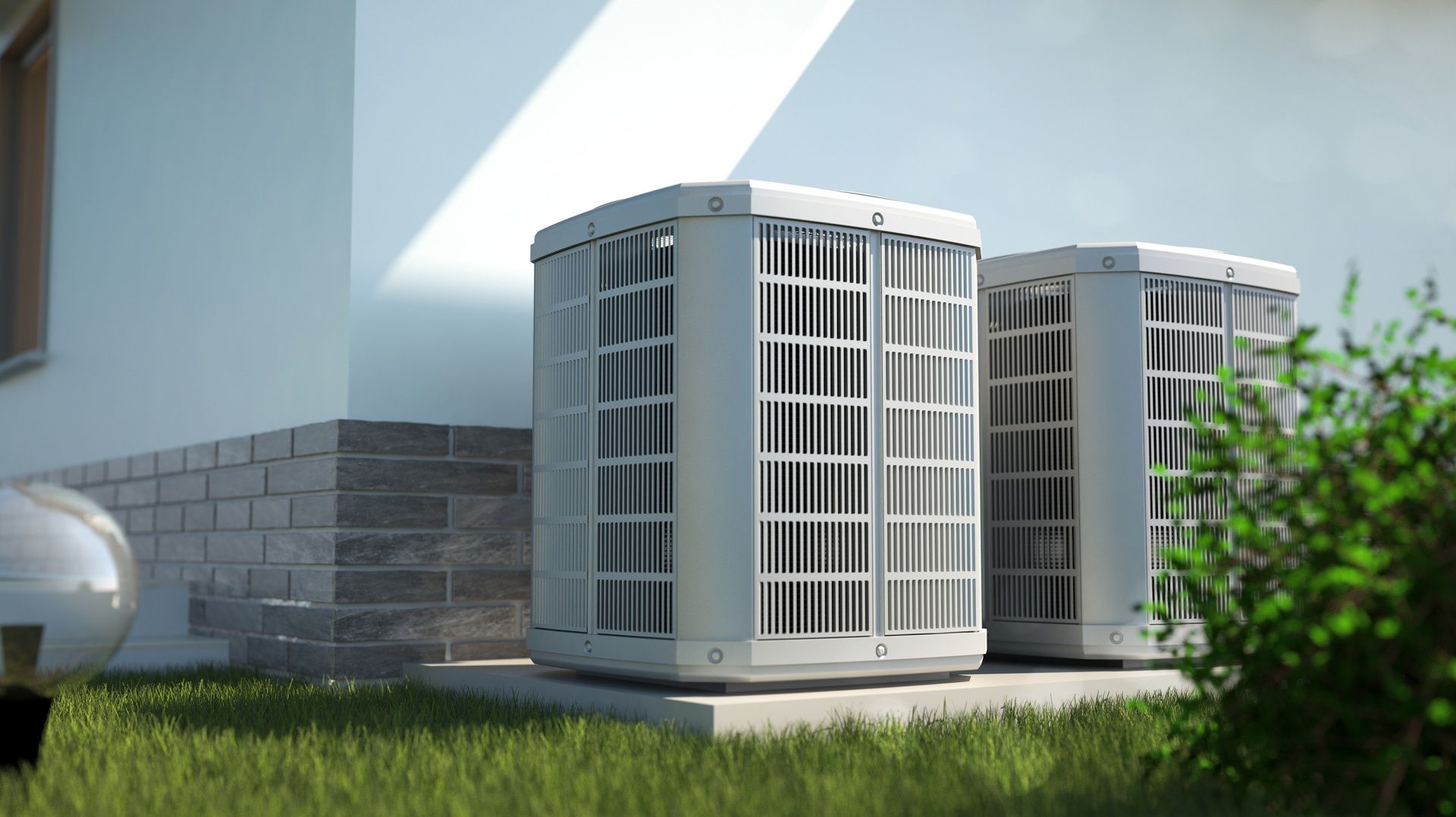 Two outdoor air conditioning units beside a house wall on a grassy lawn.