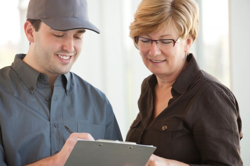Two coworkers reviewing information on a clipboard, smiling in an office setting.