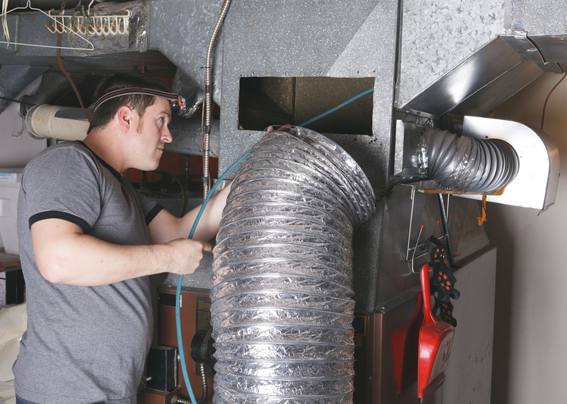 Technician inspecting HVAC ductwork inside a metal-lined mechanical room