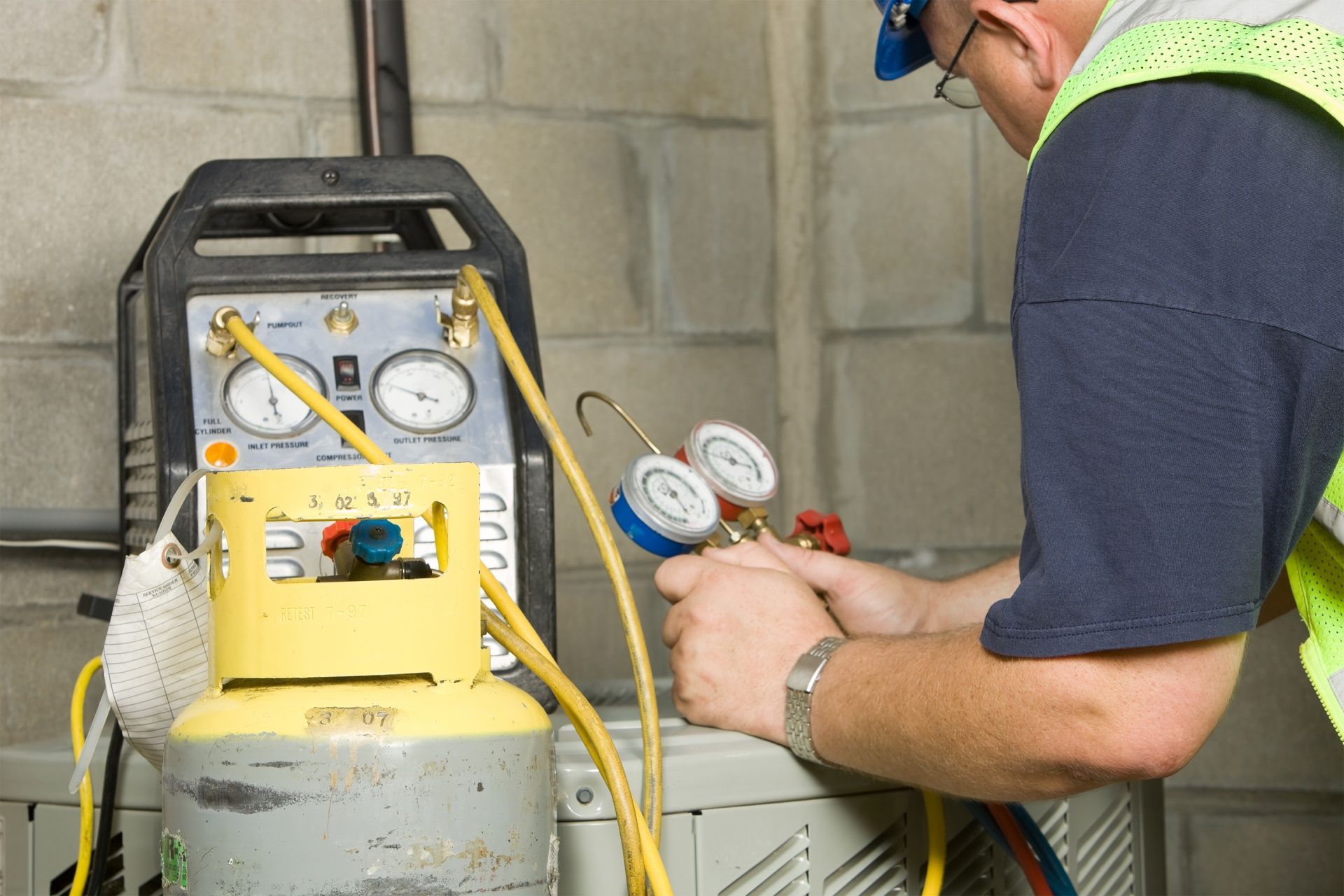 Technician checking gauges on a yellow industrial tank with hoses in a workshop