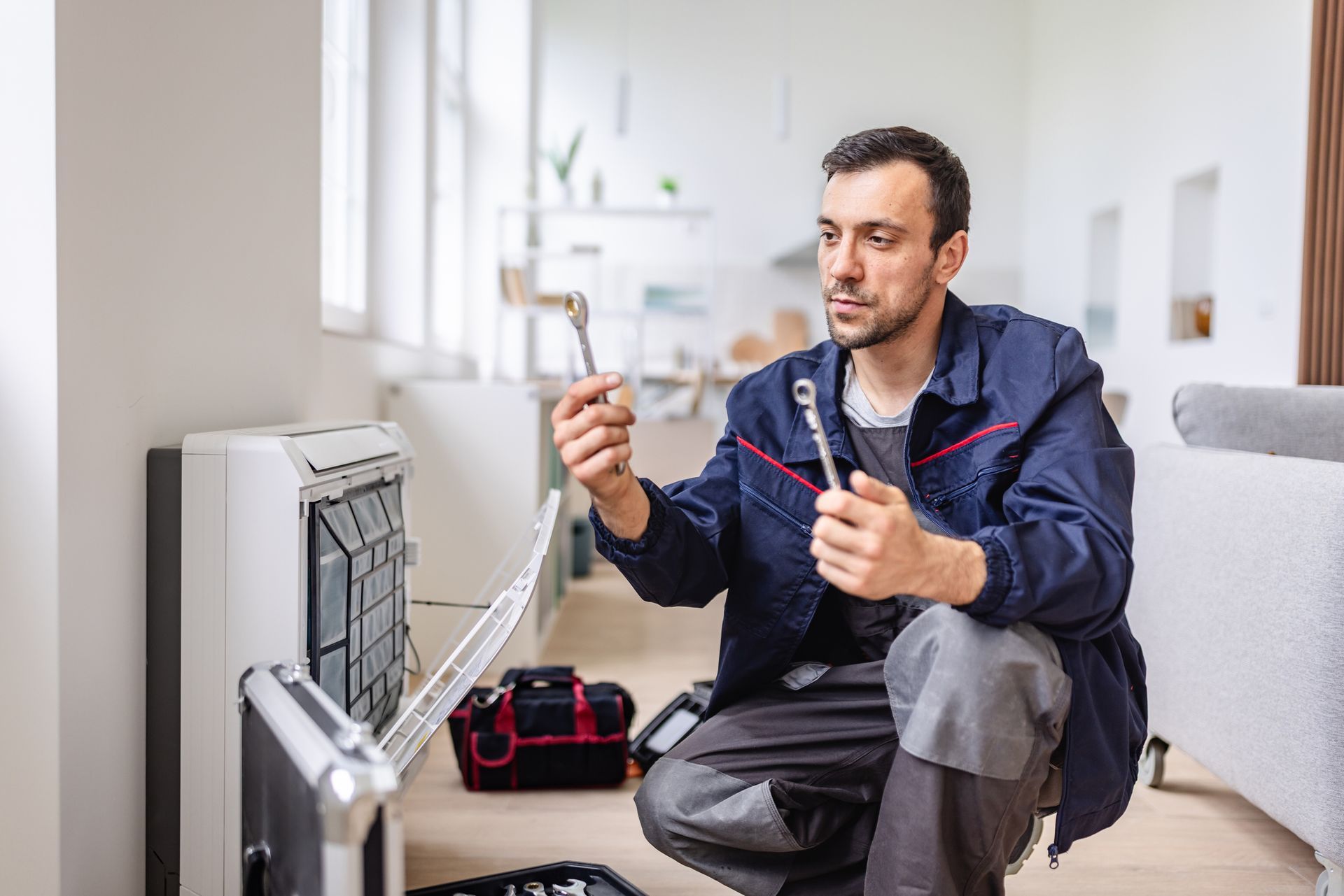 HVAC technician repairing an indoor air conditioning unit while evaluating system performance.