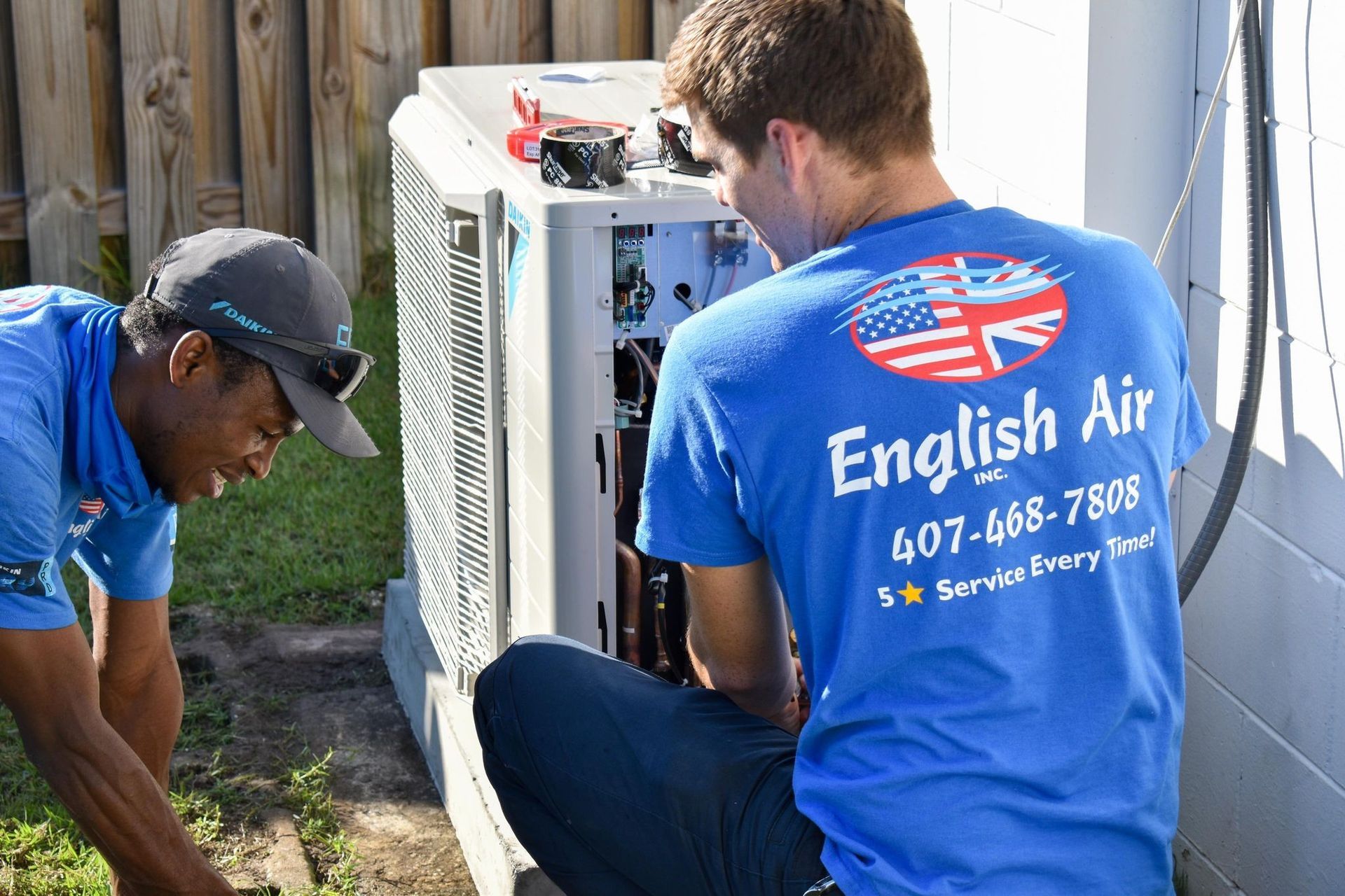 Two technicians in blue shirts servicing an outdoor English Air unit