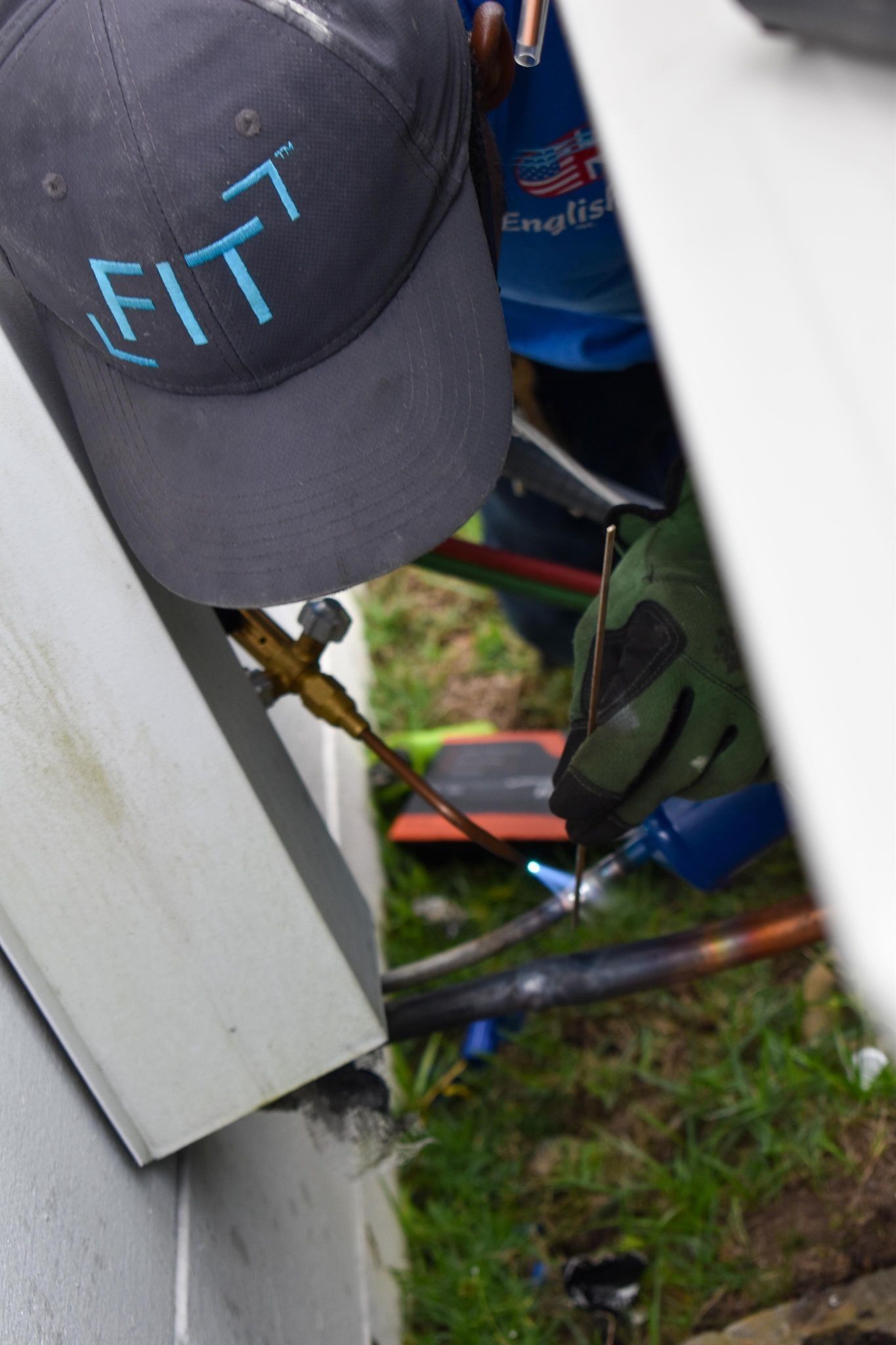 Close-up of gray FIT cap and gear beside a blue can on the ground outdoors