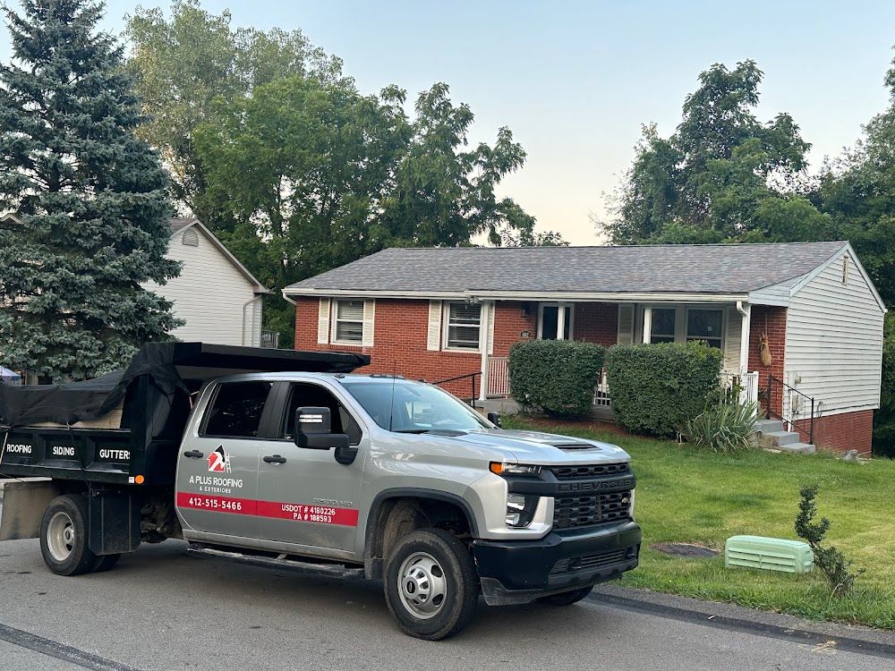 Silver dump truck in front of a brick house, likely for debris removal.