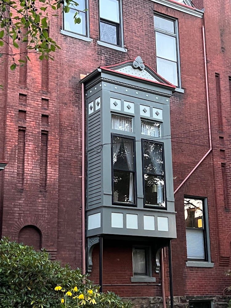 Brick building with a gray and white bay window.