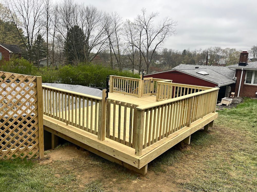 Wooden deck with railings in a backyard. The deck is newly built and elevated, with a lattice panel on the left.