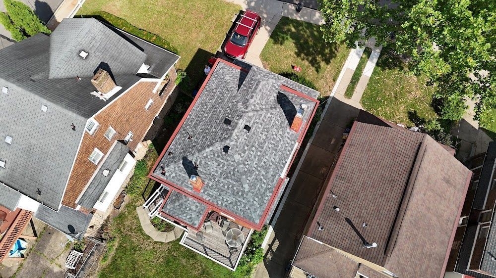Overhead view of several houses with different colored roofs and a red car parked on the street.