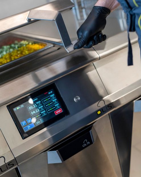 Showroom di cucine moderne in acciaio inox con isola centrale e ampie vetrate.