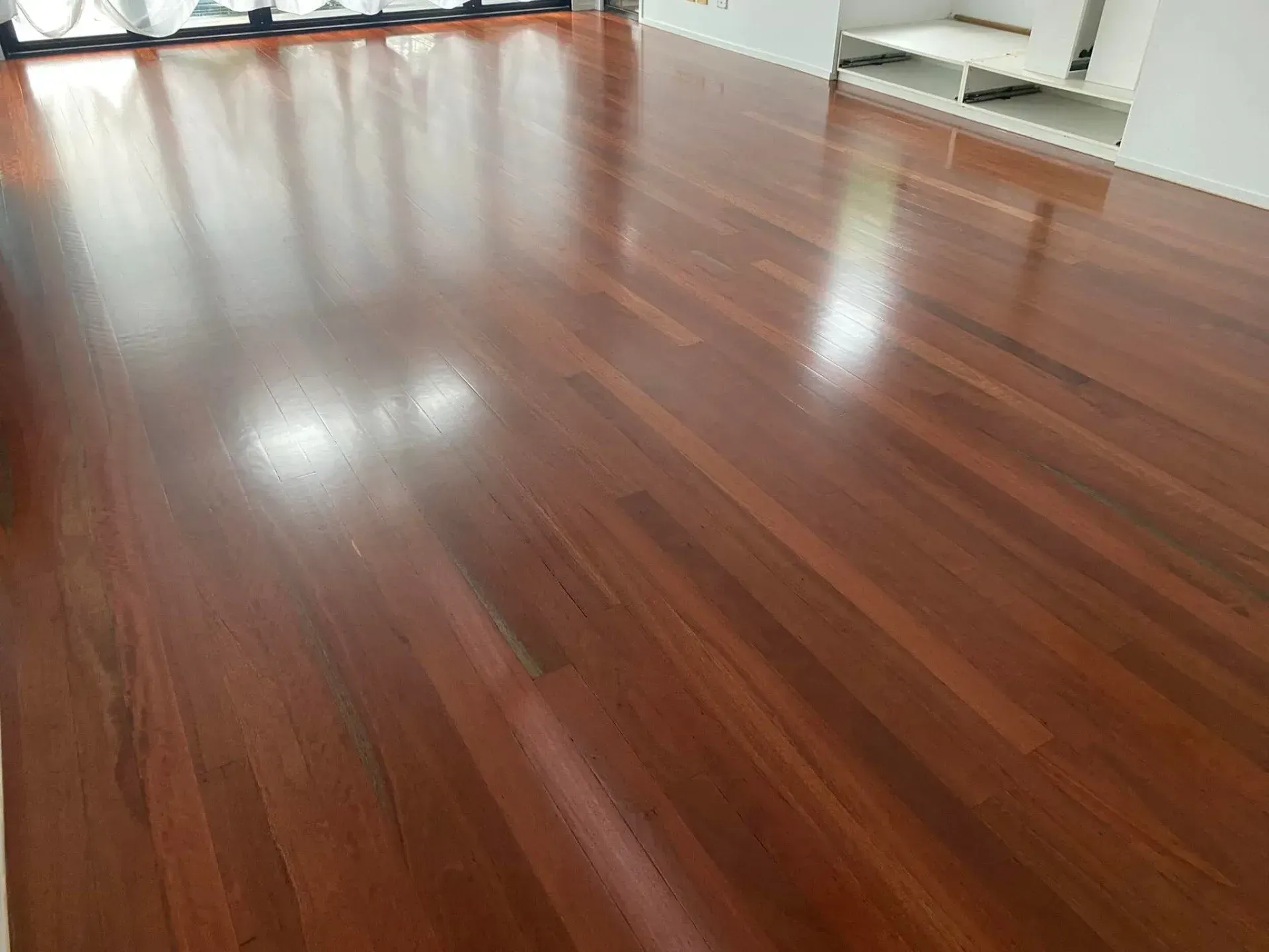 A Living Room With A Wooden Floor And A Window — AJ's Cleaning & Floor Sanding In Woree, QLD