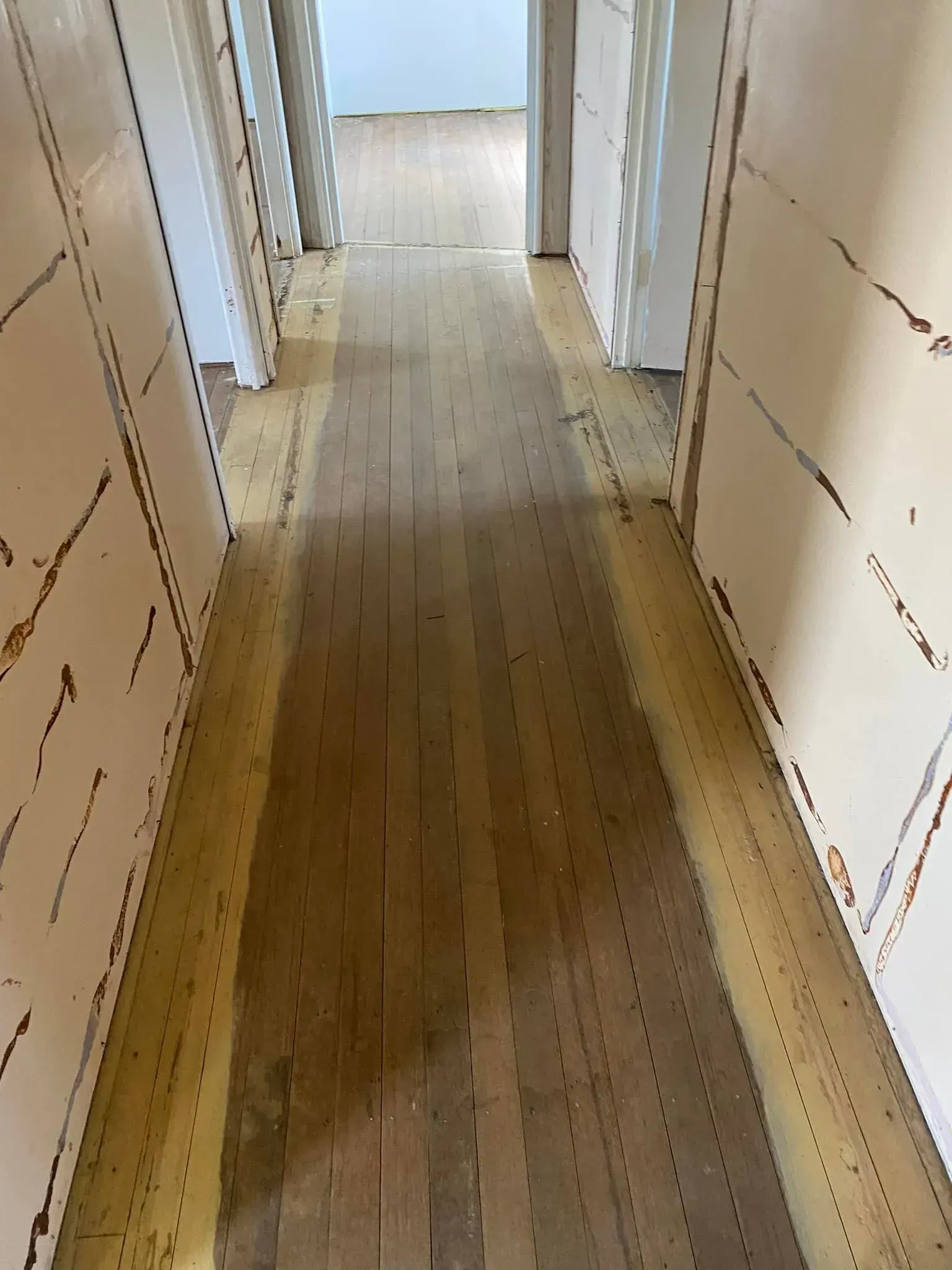 A Long Hallway With Wooden Floors And White Walls — AJ's Cleaning & Floor Sanding In Woree, QLD