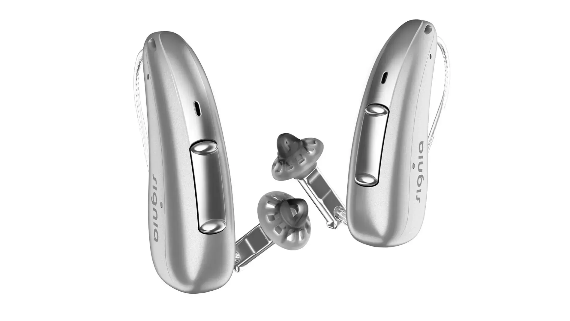 Pair of silver hearing aids with earpieces on a white background