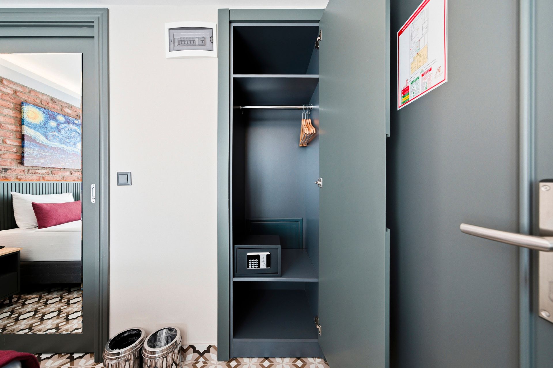 ARTELIST HOTEL | Open closet with shelves and hanging space in a gray room, beside an open doorway to a bedroom.