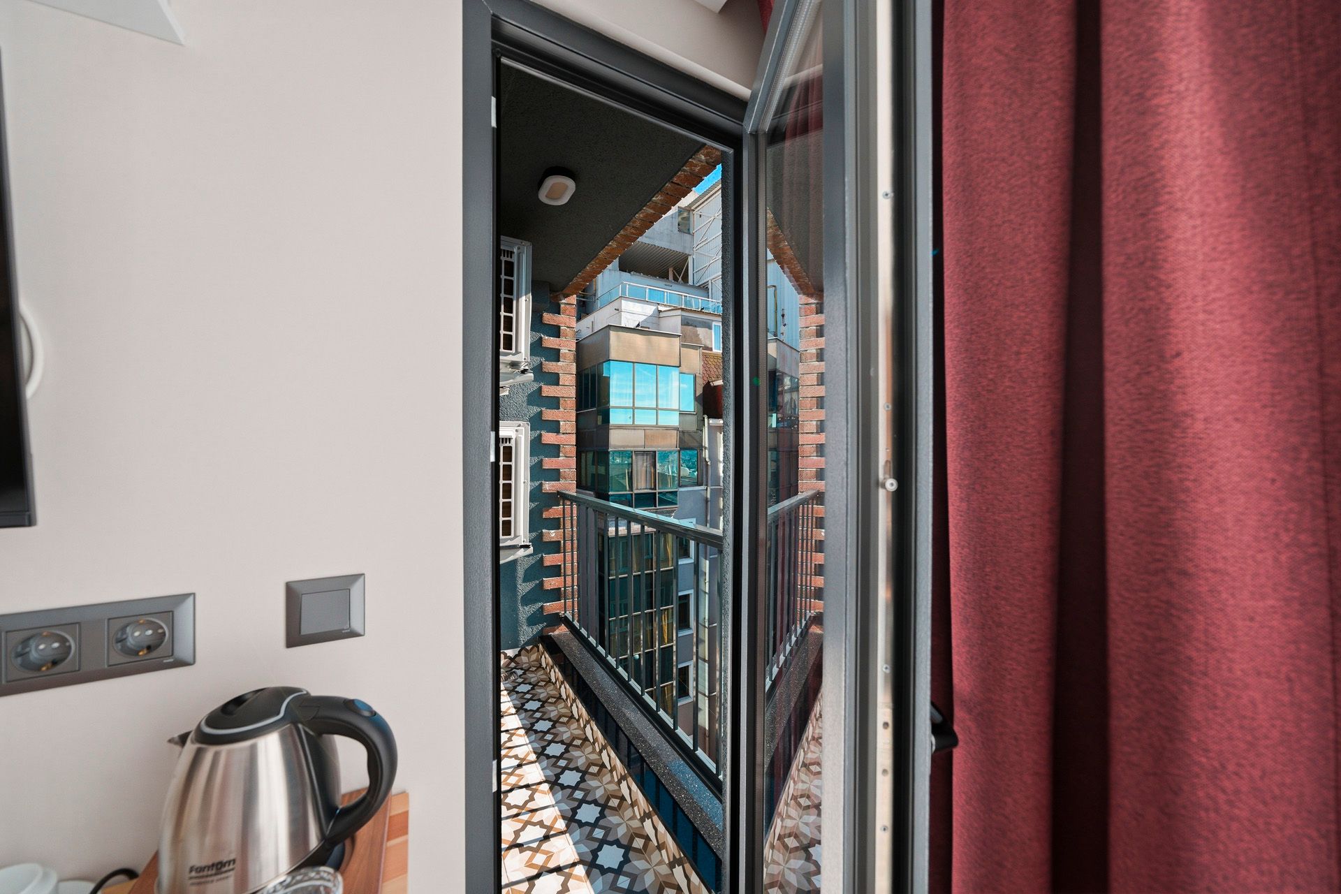 ARTELIST HOTEL | Apartment balcony view through an open door, with red curtains and a patterned floor.