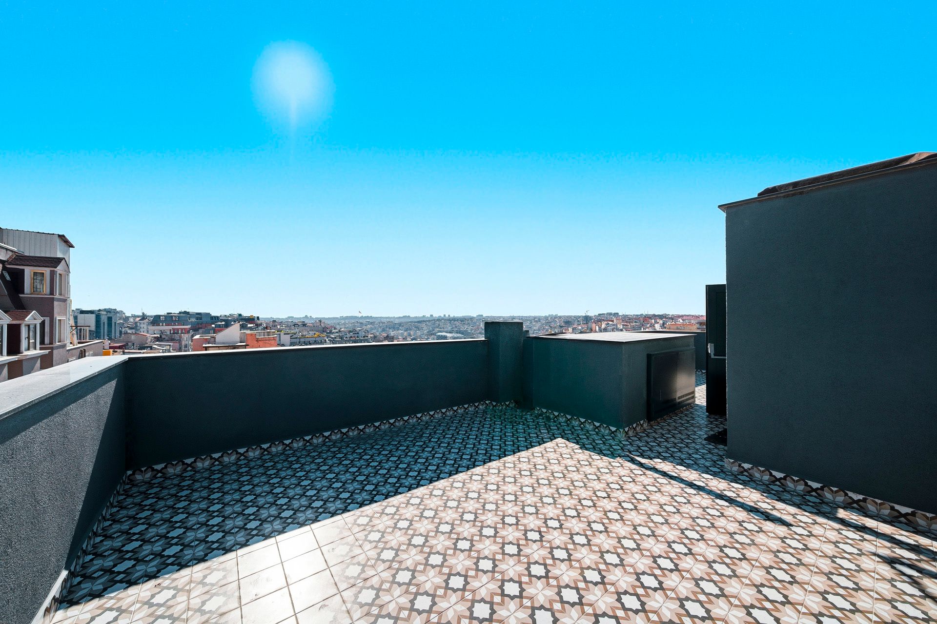 ARTELIST HOTEL | Rooftop terrace with patterned tile floor, low walls, and city skyline under a bright blue sky