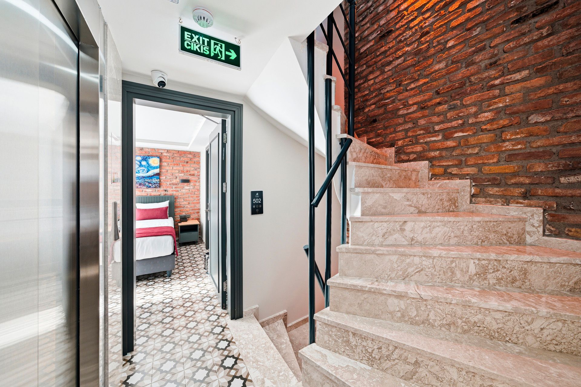 ARTELIST HOTEL | Stairwell with red brick wall, stone steps, and a hallway leading to a bedroom with a bed visible