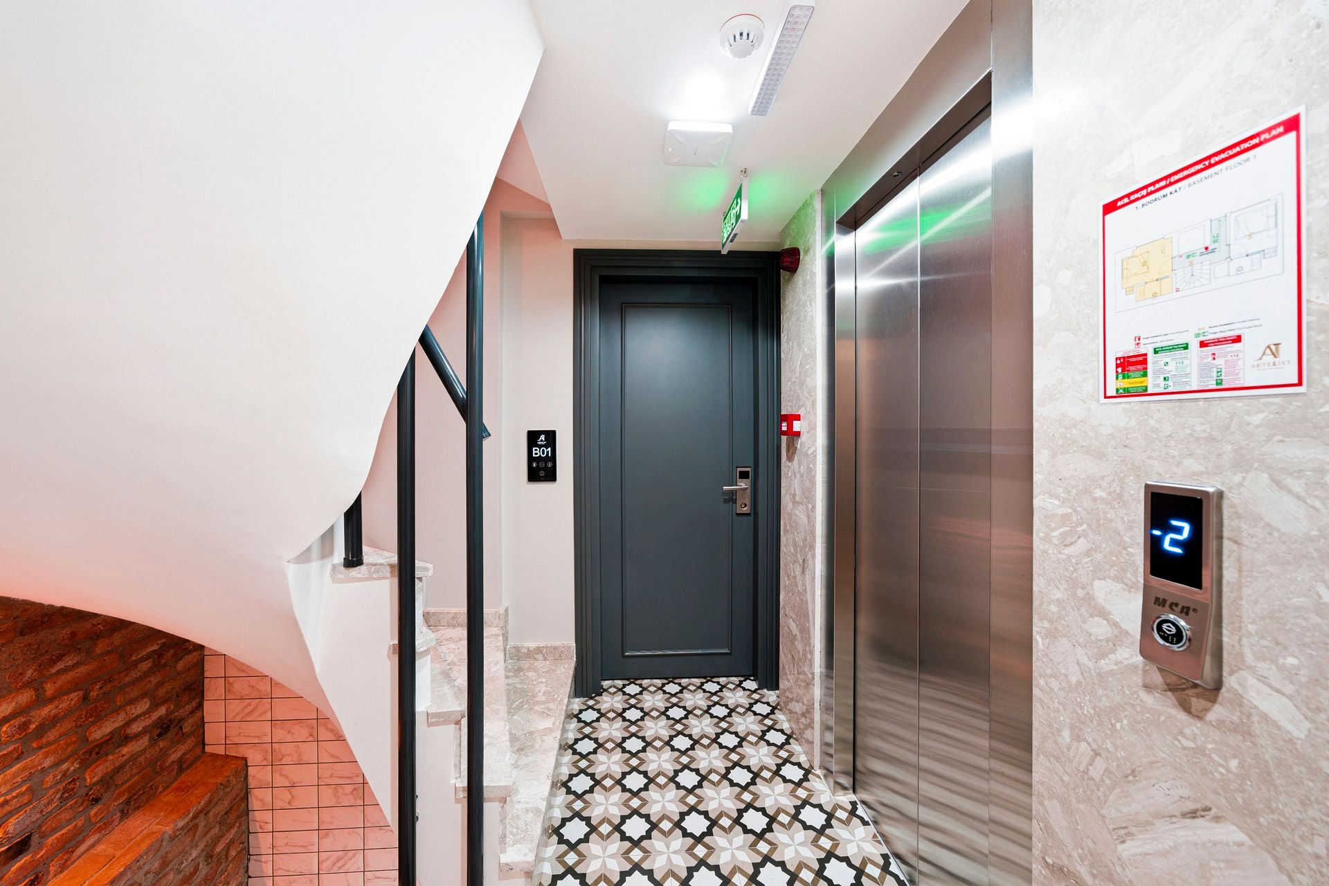 ARTELIST HOTEL | Modern apartment hallway with elevator, patterned tile floor, and staircase