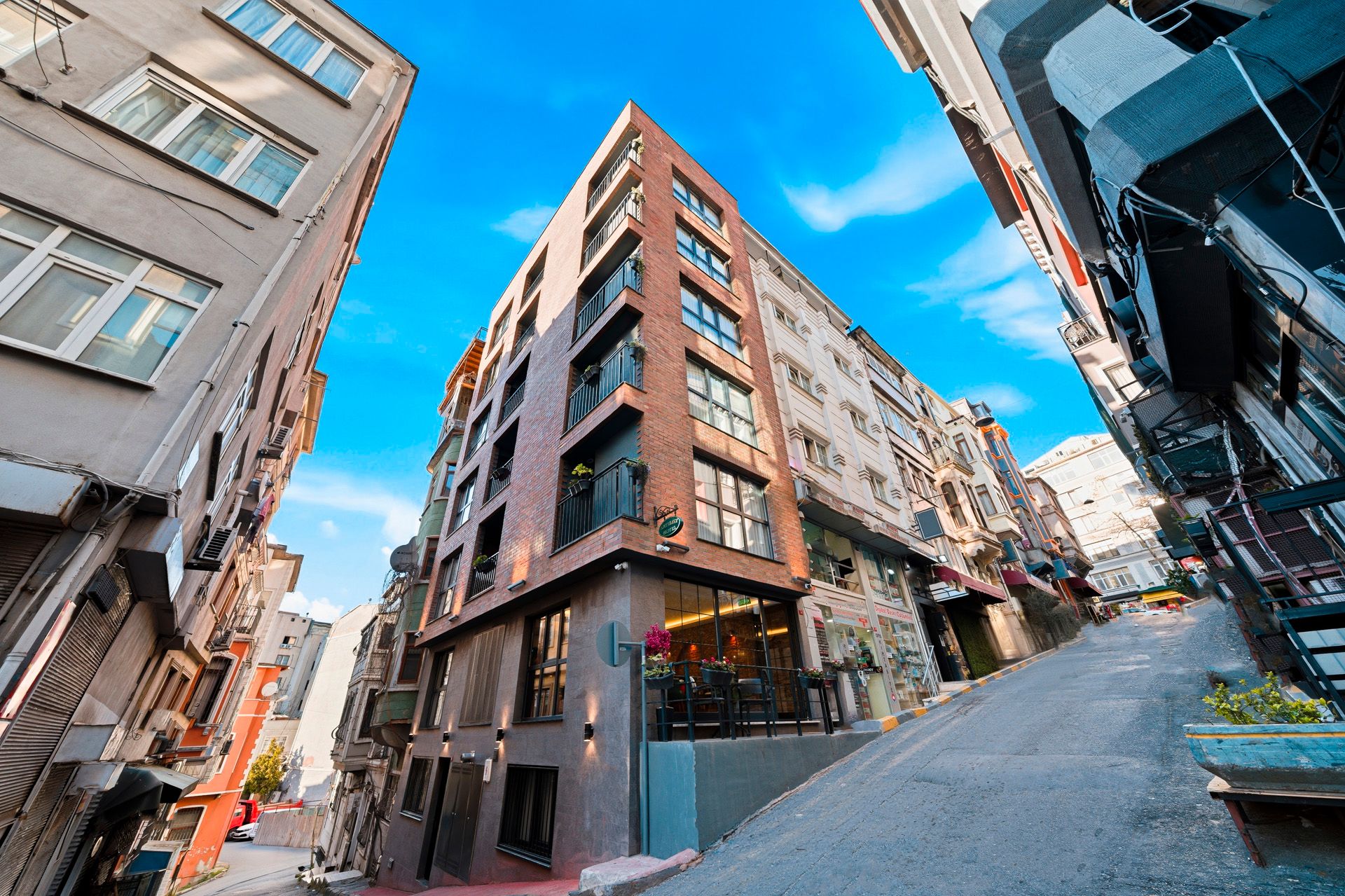 ARTELIST HOTEL | Narrow city street with tall apartment buildings under a bright blue sky