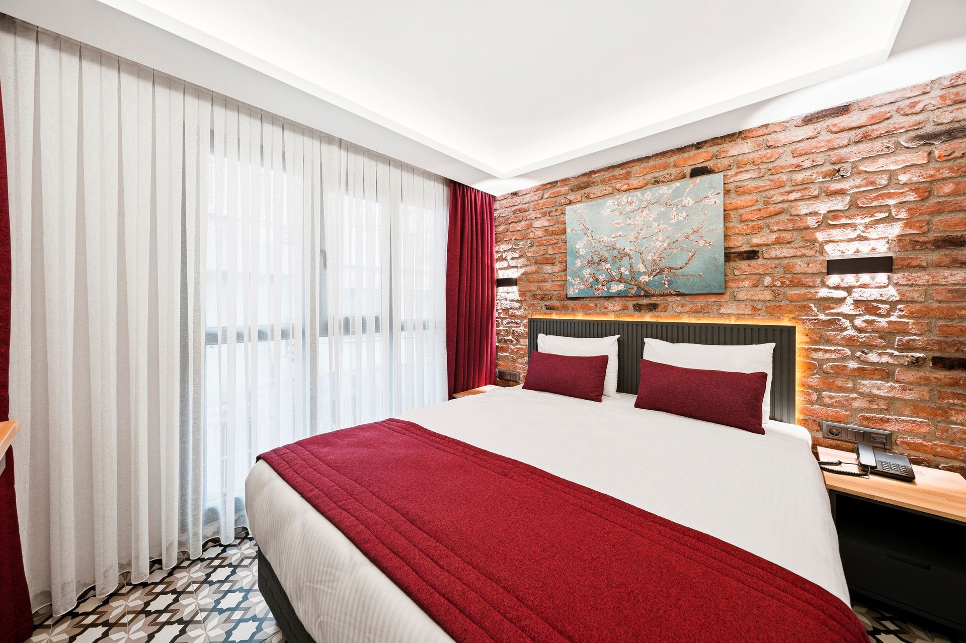  ARTELIST HOTEL | Room, Modern bedroom with red bedding, brick accent wall, and sheer white curtains