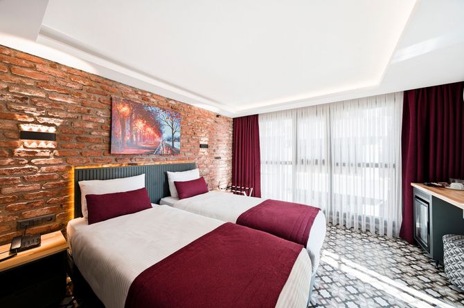 ARTELIST HOTEL | Modern hotel bedroom with brick accent wall, king bed, and floor-to-ceiling curtains