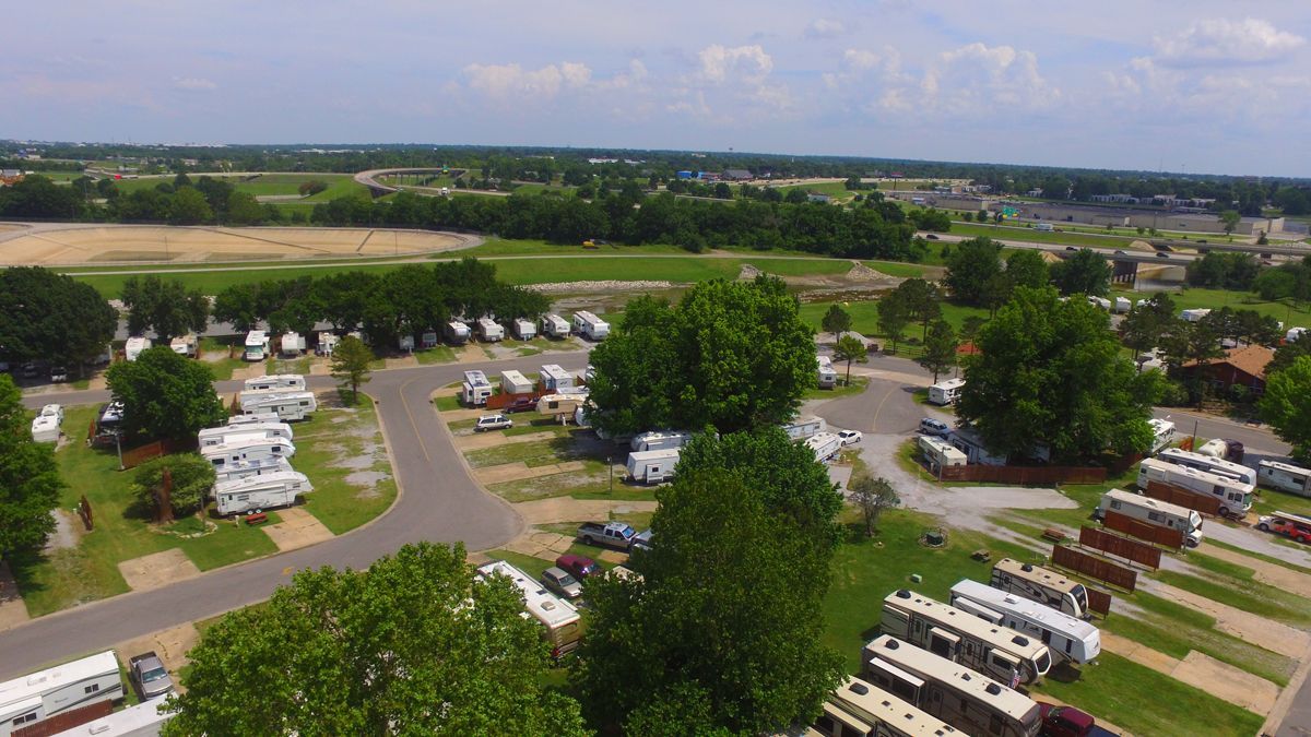 An aerial view of a campground with a lot of rvs parked in the grass.
