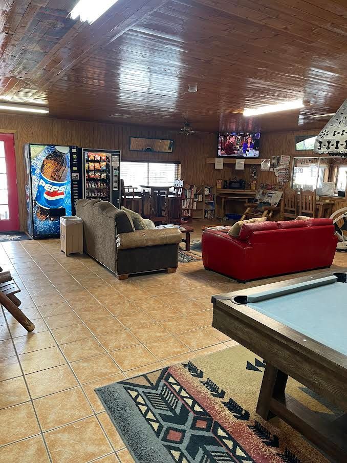 A living room with a pool table , couch , and vending machine.