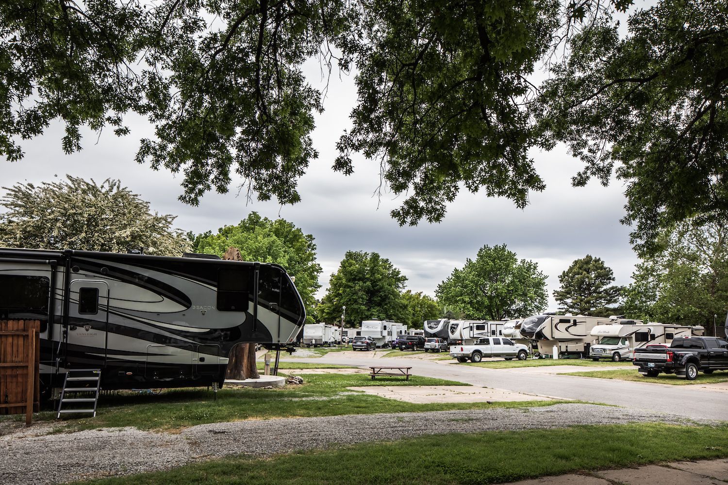 A rv is parked in a lot with trees in the background.
