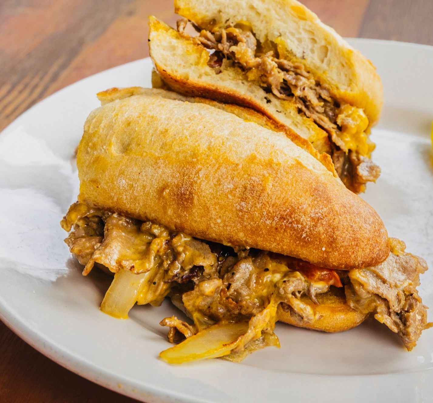 Sandwich filled with shredded meat and onions on a white plate
