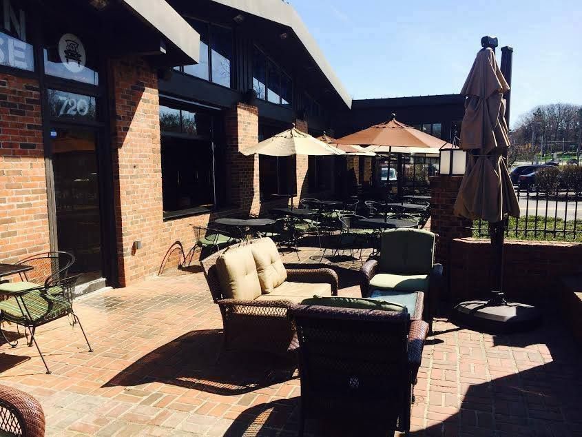 A patio with furniture and umbrellas in front of a brick building