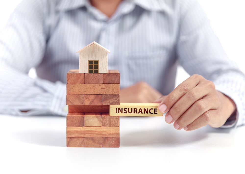 A Hand Pushing Wooden Brick with the Word Insurance on it — Clarence Property Consultants In Grafton, NSW
